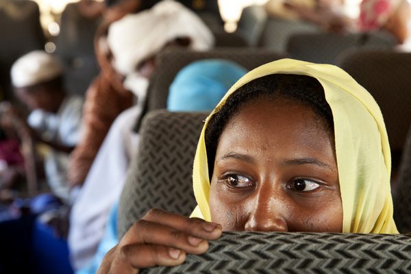 Internally Displaced Persons (IDPs) ride a bus to return from the IDP camp in Aramba to their original village in Sehjanna, near Kutum, North Darfur. The voluntary repatriation program is organized by the Office of the United Nations High Commissioner for Refugees (UNHCR) and the Sudanese Humanitarian Aid Commission.